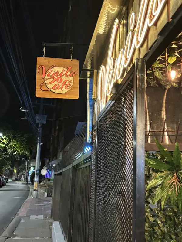 Fachada de Vinilo & Café de noche, con su aviso iluminado