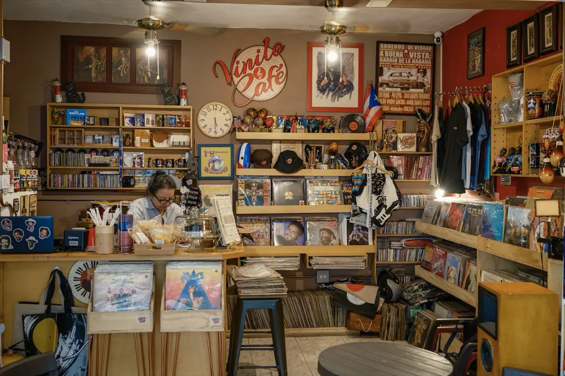Interior de Vinilo & Café con paredes rojas, estantes llenos de discos, afiches y el logo al fondo