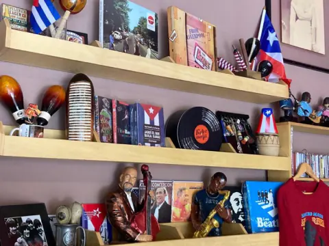 Repisas con discos, banderas de Cuba y Puerto Rico y figuras de músicos