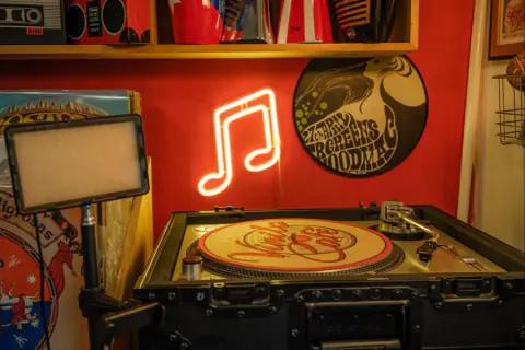 Tornamesa con un disco de Vinilo & Café y una nota musical en neón